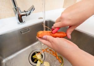 Kitchen sink and garbage disposal with holiday cooking supplies nearby, illustrating common causes of seasonal plumbing clogs.
