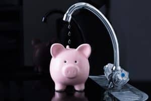 Water leak falling into a piggy bank showing money wasted