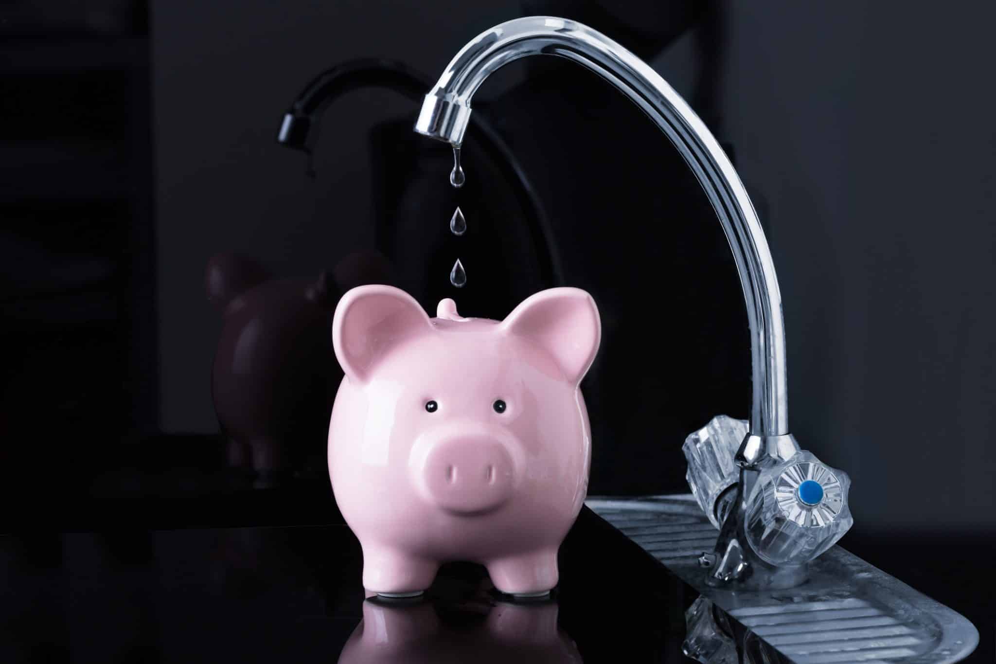 Water leak falling into a piggy bank showing money wasted